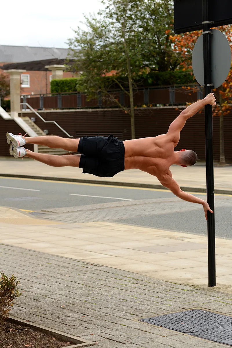 Alex Rabia performing the human flag — the figure in the AR monogram